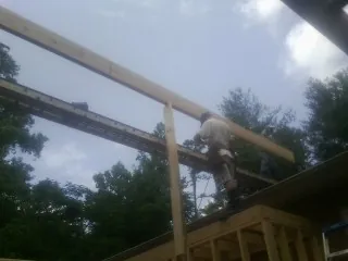 Carpenter setting a ridge beam over a new addition frame — Ice Dam Removal by Roofing Brothers in Delcambre