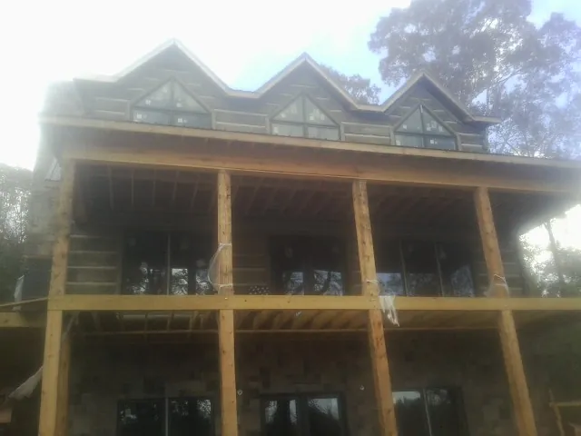 Dormers and porch framing on a large log home under construction — Roof Coating work by our crew in Delcambre