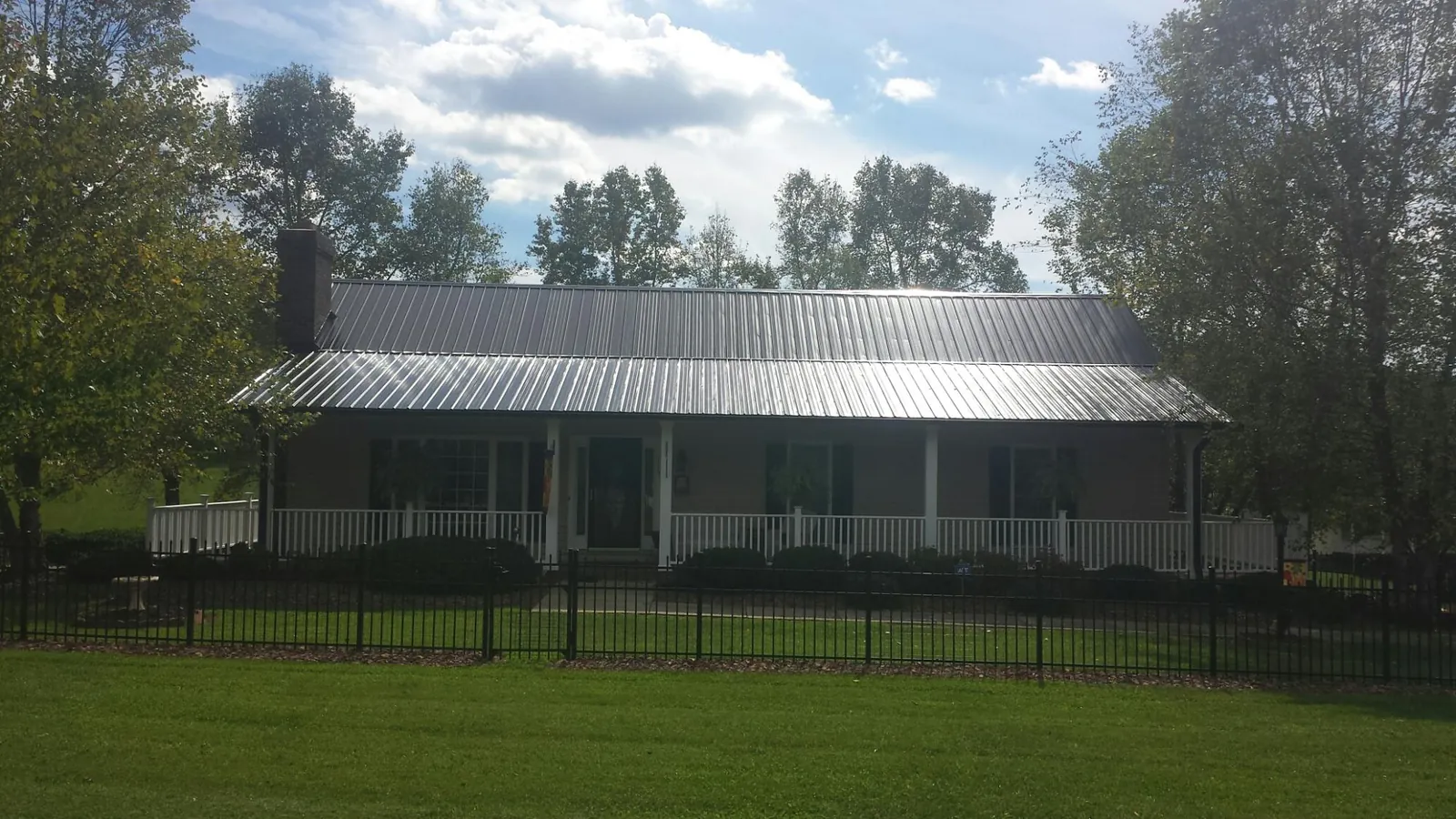 Gray metal roof on a brick ranch with a full width front porch — Gutter Guard Installation work by our crew in Delcambre