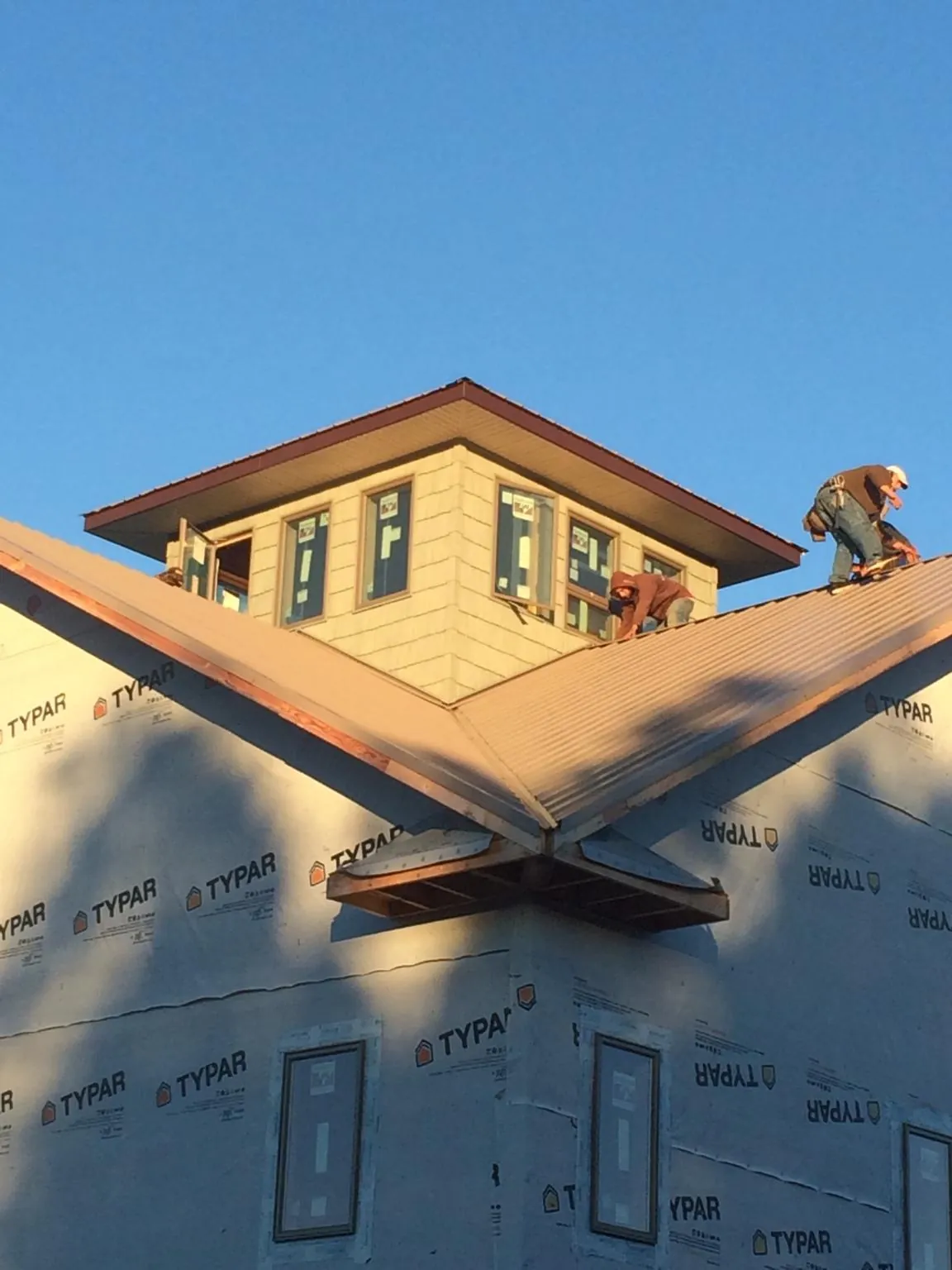 Roofers working around a rooftop cupola on a new metal roof at sunset — Roof Waterproofing in Delcambre by Roofing Brothers